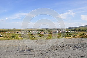 White clouds in the bright blue summer sky over village with small houses far away in the mountains and fields. Travelling. Peopl