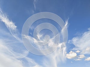 White clouds disperse on blue sky background.