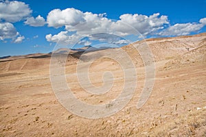 White clouds float over the arid landscape in a valley