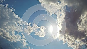 White clouds flying on blue sky with sun rays motion background