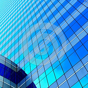 White clouds reflect sunlight on tall glass blue abstract crop of modern office skyscraper texture and bacgound.