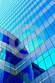 White clouds reflect sunlight on tall glass blue abstract crop of modern office skyscraper texture and bacgound.