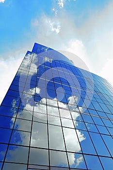 White clouds reflect sunlight on tall glass blue abstract crop of modern office skyscraper texture and bacgound.