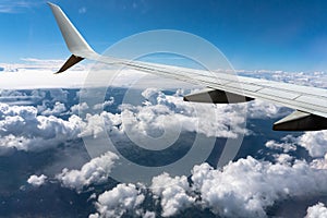 White clouds sail under the wing of an airplane