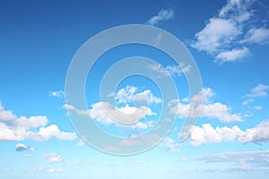 White clouds of various shapes against the blue sky and the sun above the surface of the ocean.