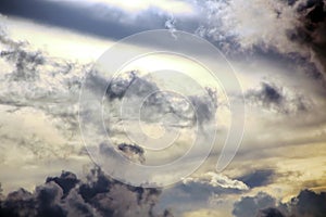 White clouds of various shapes against the blue sky and the sun above the surface of the ocean.