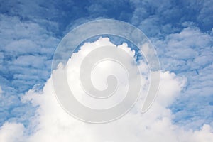 White clouds of various shapes against the blue sky and the sun above the surface of the ocean.