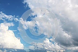 White clouds of various shapes against the blue sky and the sun above the surface of the ocean.