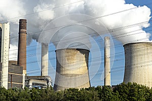White clouds of water vapor emerging from the cooling tower of a power generating plant.