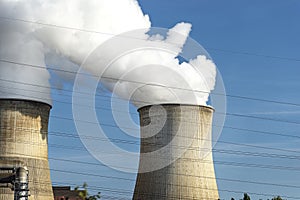 White clouds of water vapor emerging from the cooling tower of a power generating plant.