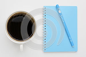 White coffee cup and blue notebook,pen on white background,top view