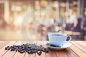 White coffee cup and coffee beans on wood table with blurred bac