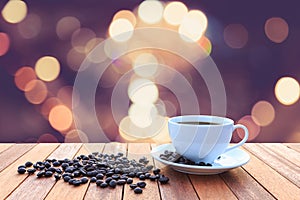 White coffee cup and coffee beans on wood table with blurred bac