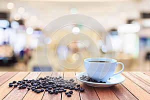 White coffee cup and coffee beans on wood table with blurred bac