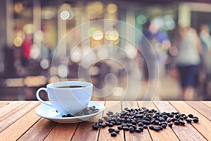 White coffee cup and coffee beans on wood table with blurred background
