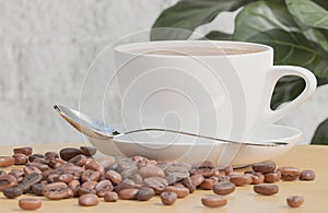 White Coffee cup and coffee beans on wood table with plant and white brick wall background