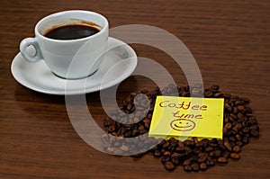 White coffee cup and coffee beans on a wooden table.Coffee time