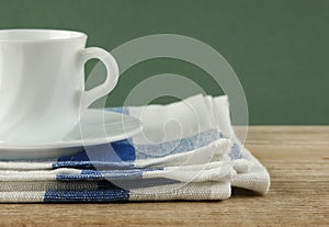 White coffee cup and dishcloth on old wooden table