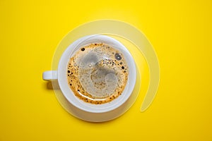 White coffee Cup with foam on a bright yellow background top view