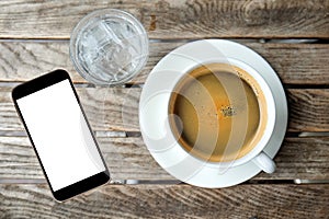 White coffee cup and glass water with smart phone on wooden.