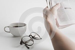 White coffee cup,glasses,and a man read News paper on the white table