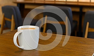 White coffee cup with hot cappuccino coffee on wooden table in coffee cafe. copy space for adding text