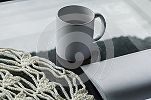 White coffee cup placed on an office table next to a book with its blank pages ready to copy text