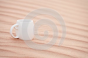 White coffee cup in sahara sand dune