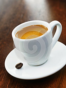 White coffee cup and saucer with single bean