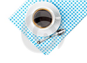 White coffee cup with saucer and spoon tableware on blue chequered napkin