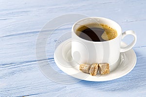 White Coffee cup side view on old wooden table. Aromatic coffee drink in white cup on light blue wooden table