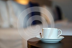 White coffee cup on the table by a sofa couch in hotel room