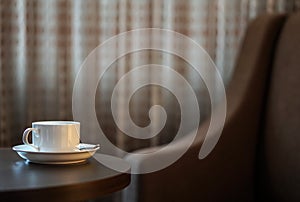 White coffee cup on the table by a sofa couch in hotel room