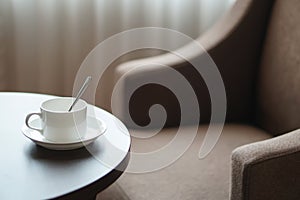 White coffee cup on the table by a sofa couch in hotel room