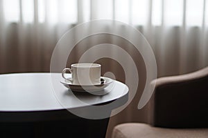 White coffee cup on the table by a sofa couch in hotel room