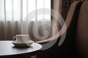 White coffee cup on the table by a sofa couch in hotel room