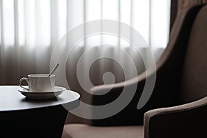 White coffee cup on the table by a sofa couch in hotel room