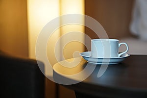 White coffee cup on the table by a sofa couch in hotel room