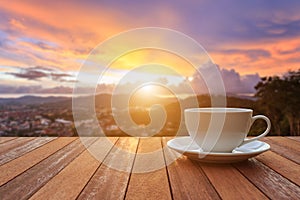 White coffee cup on wood table and view of sunset or sunrise background