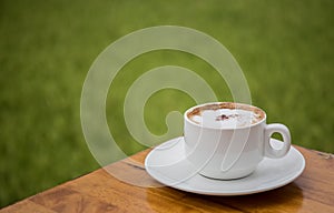 A white coffee cup on a wooden table With a backdrop of rice fields