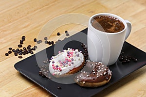 White coffee cup on a wooden table with chocolate and white chocolate donuts . Morning espresso. Morning cappuccino mug.