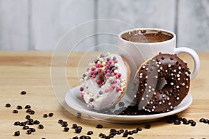 White coffee cup on a wooden table with chocolate and white chocolate donuts . Morning espresso. Morning cappuccino mug.