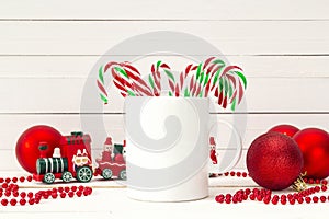 White coffee mug with candy canes and Christmas decorations on w