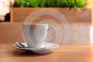 White coffee mug on a saucer with a spoon
