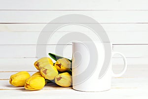 White coffee mug with yellow tulip flowers on white background