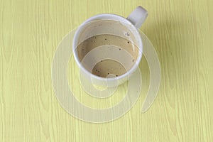 White coffee mugs morning light On the floor of a yellow wooden table Coffee bubbles in a clean, clean glass Breakfast. Placed in