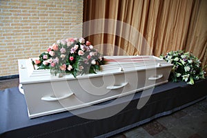 White coffin with pink sympathy flowers