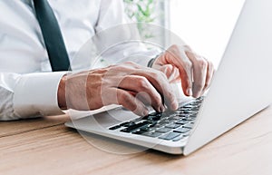 White collar worker typing laptop computer keyboard at office desk