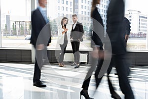 White collar workers going down office corridor during working day.