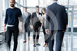 White collar workers going down office corridor during working day.